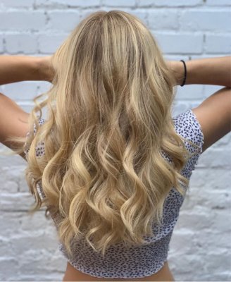 Girl with long blonde hair from behind holding uo her hair showing off a balayage.