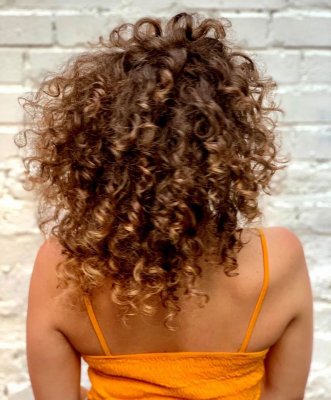 Girl with an orange top and curly hair at the klinik salon
