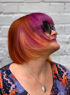 A girl with a multi coloured bob in tones of copper, pink, purple and yellow, wearing sunglasses at the klinik salon London