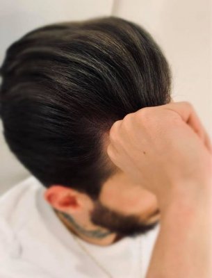 A guy sitting in a white tshirt showing off his slate grey highlights at the klinik salon London