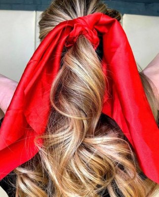 Blonde hair ponytail with large red bow at the klinik salon London