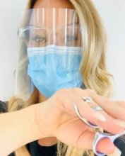 Hairdresser with face visor and mask showing off her scissors at the klinik hairdressers