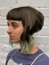 Girl with a disconnected bob with long pieces at the front and shaved back with green tips at the klinik salon London